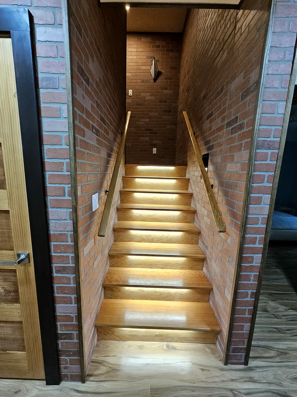 Interior staircase with brick accent wall and recessed lighting